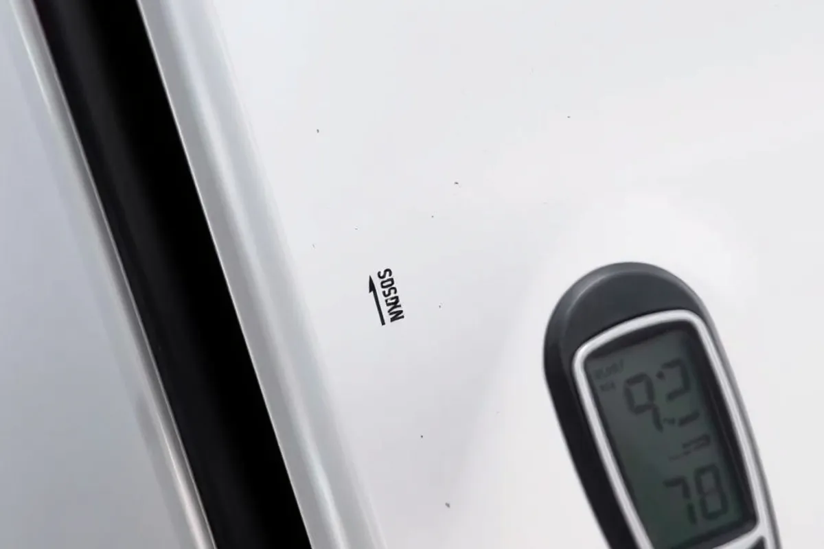 Buyer checking paint thickness on a used car panel